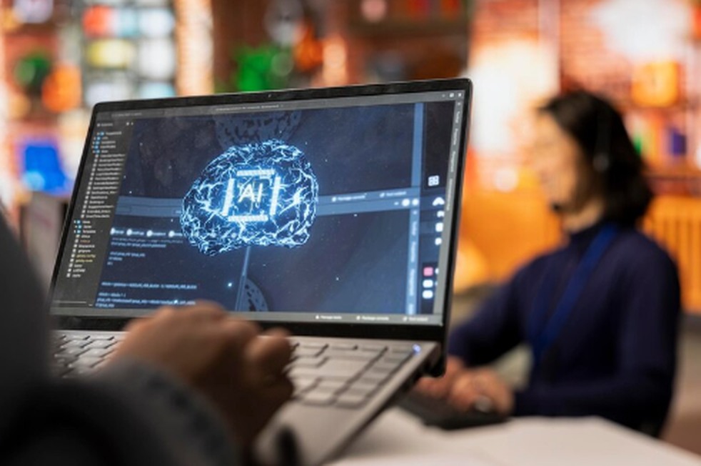A close-up of a laptop screen displaying a glowing AI brain graphic with code in the background, while a professional works in a modern office setting—symbolizing the technological innovation driving interest in Artificial Intelligence ETFs.