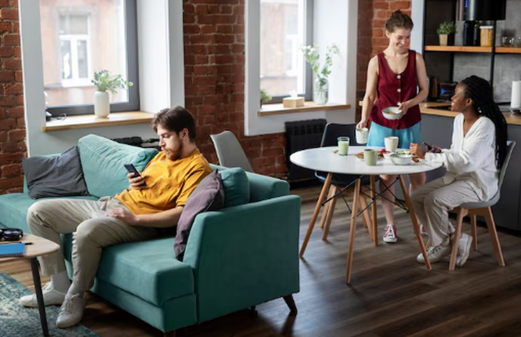Three young adults interacting in a modern shared apartment, illustrating the social and communal lifestyle associated with co-living.