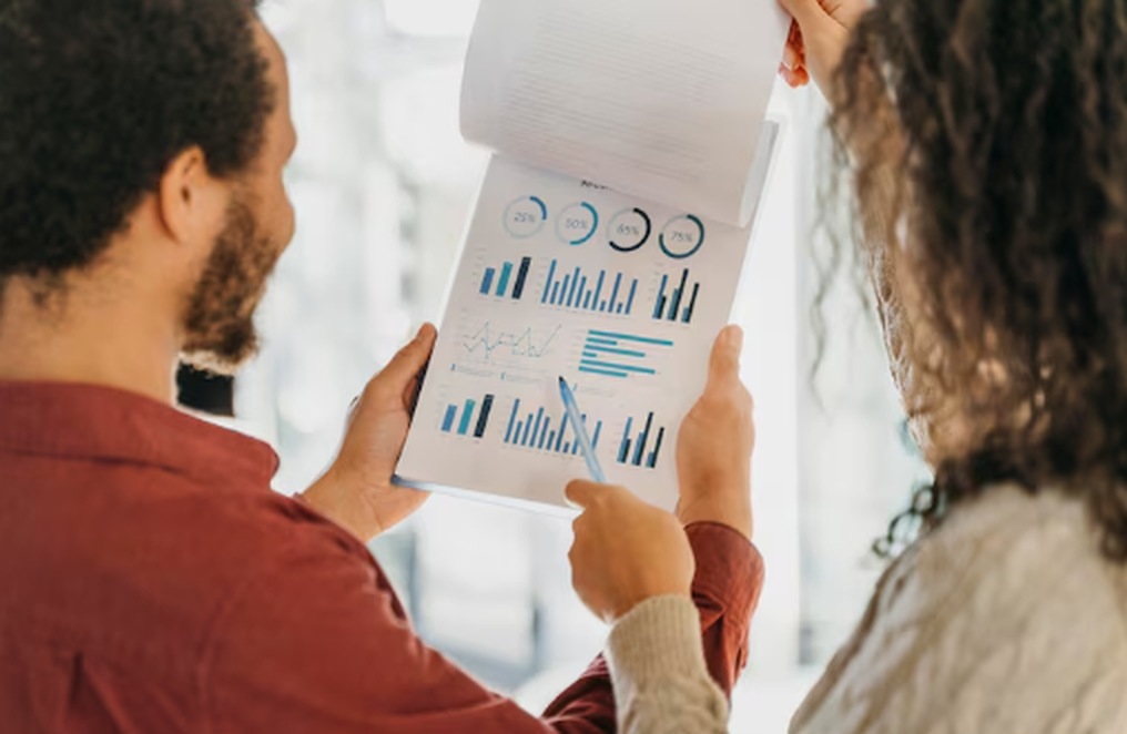 Two colleagues reviewing a printed report with charts and graphs, illustrating the use of quantitative analysis for data-driven decision-making.