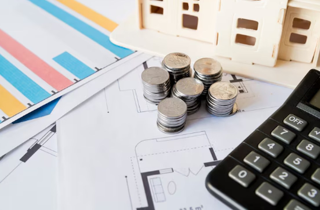Stacks of coins, financial charts, and a calculator on a desk, symbolising investment strategies and the growing role of real-world asset tokens in modern finance.